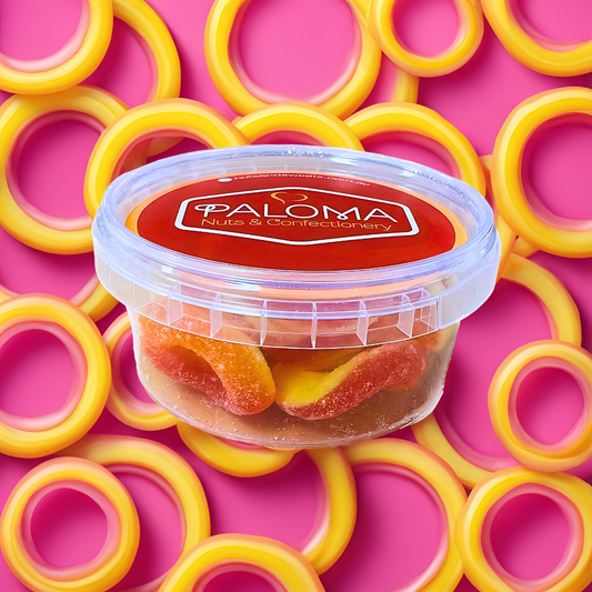 Clear plastic container of gummy candy labeled ’Paloma’ surrounded by yellow ring-shaped objects on a pink background.